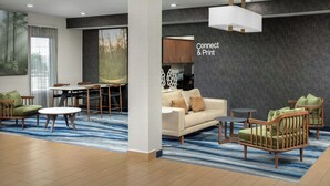 A modern hotel lobby with a dining area, a sofa, and a coffee table. - Fairfield Inn & Suites by Marriott Albuquerque Airport (Albuquerque)