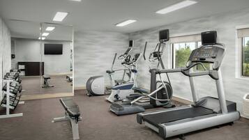 A gym with treadmills, elliptical machines, and free weights.