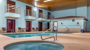 A pool area with a hot tub, lounge chairs, and a small building with a red door. - Econo Lodge West - Coors Blvd (Albuquerque)