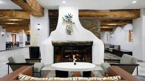 A modern lounge area with a fireplace, leather sofas, and a stone wall. - Courtyard by Marriott Albuquerque (Albuquerque)