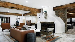 A spacious lounge area with a fireplace, comfortable seating, and exposed wooden beams. - Courtyard by Marriott Albuquerque (Albuquerque)