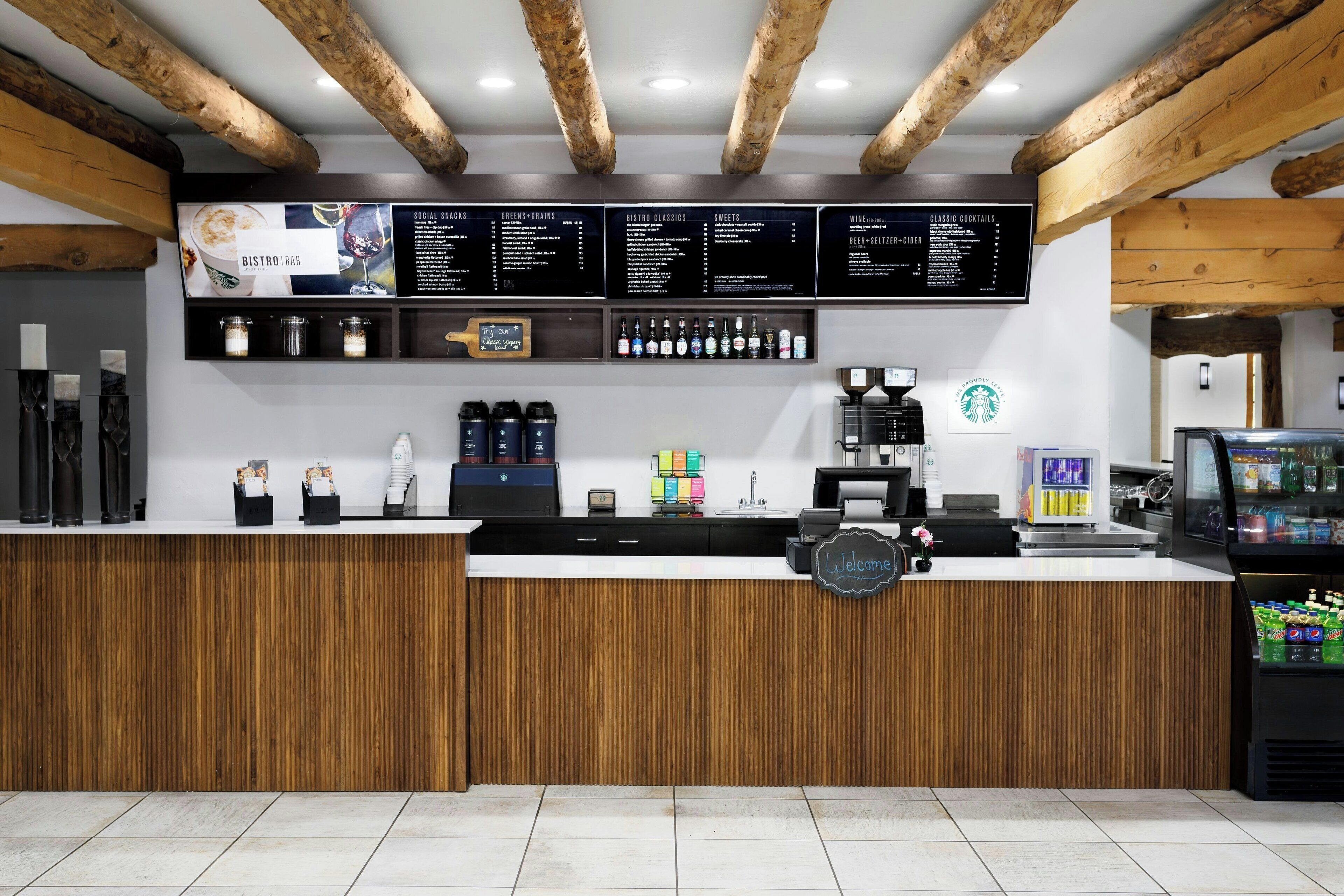 A bar area with wooden beams, a menu board, and a Starbucks coffee machine.