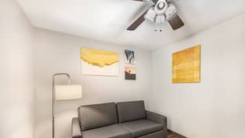 Una sala de estar moderna con un sofá gris, una lámpara de pie y tres obras de arte en la pared.