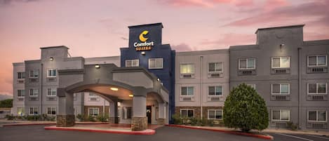 A Comfort Suites hotel with a modern architectural design, featuring a prominent entrance with a canopy, multiple windows, and a well-maintained parking area.