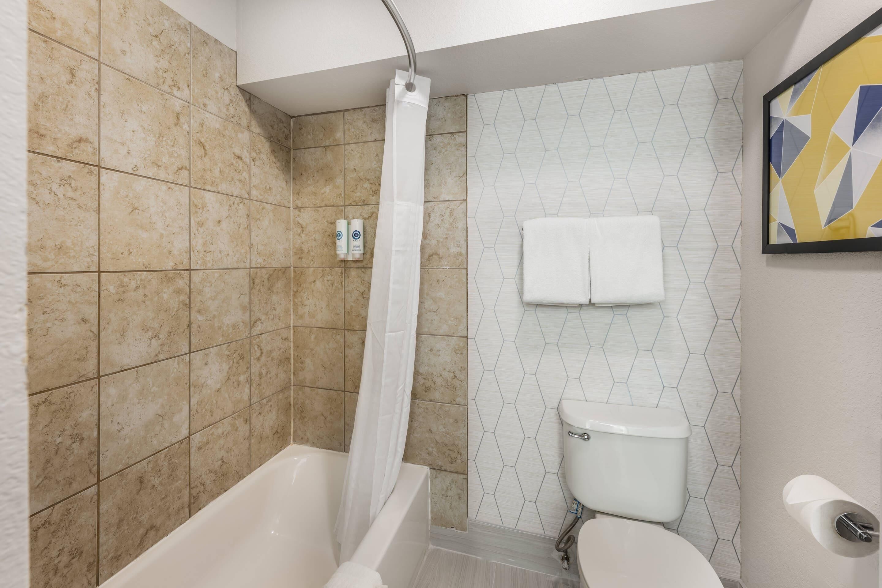 A bathroom with a bathtub, toilet, shower curtain, and a towel rack.