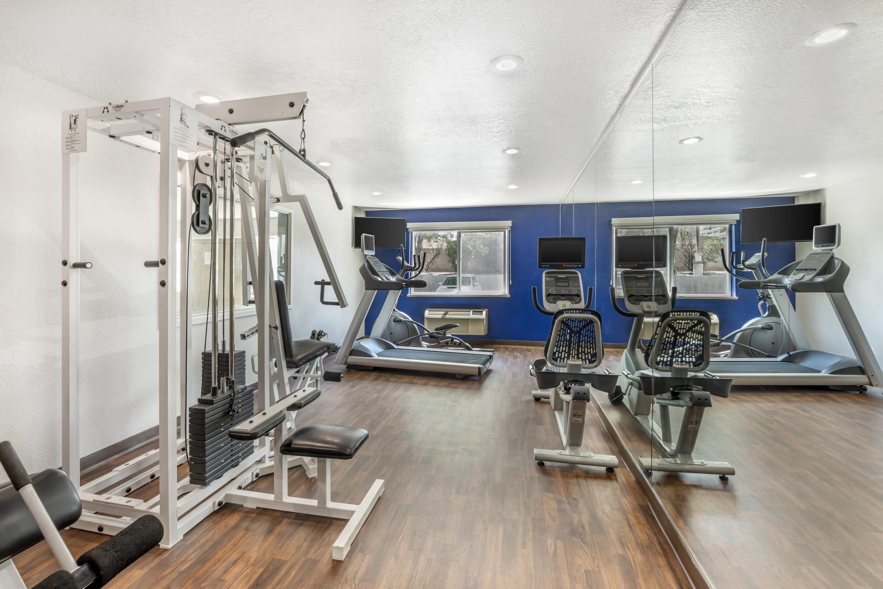 Ein Fitnessstudio mit Cardiogeräten, Krafttrainingsgeräten und einem Spiegel.