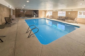 An indoor swimming pool with lounge chairs, a lifeguard stand, and a warning sign. - Comfort Suites Albuquerque/North Journal Center (Albuquerque)