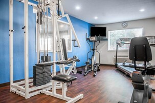 Un gimnasio con equipo de ejercicio, una cinta de correr y un espejo.