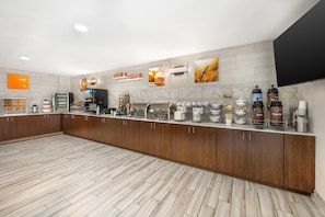 A modern kitchen area with a long counter, various appliances, and storage cabinets.