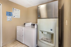 A laundry room with a front-loading washer and dryer, a stainless steel refrigerator, and a water dispenser.