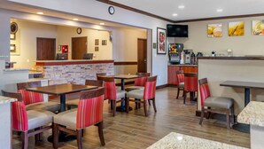 Un restaurant avec un mur en briques, des tables en bois et des chaises à rayures rouges.