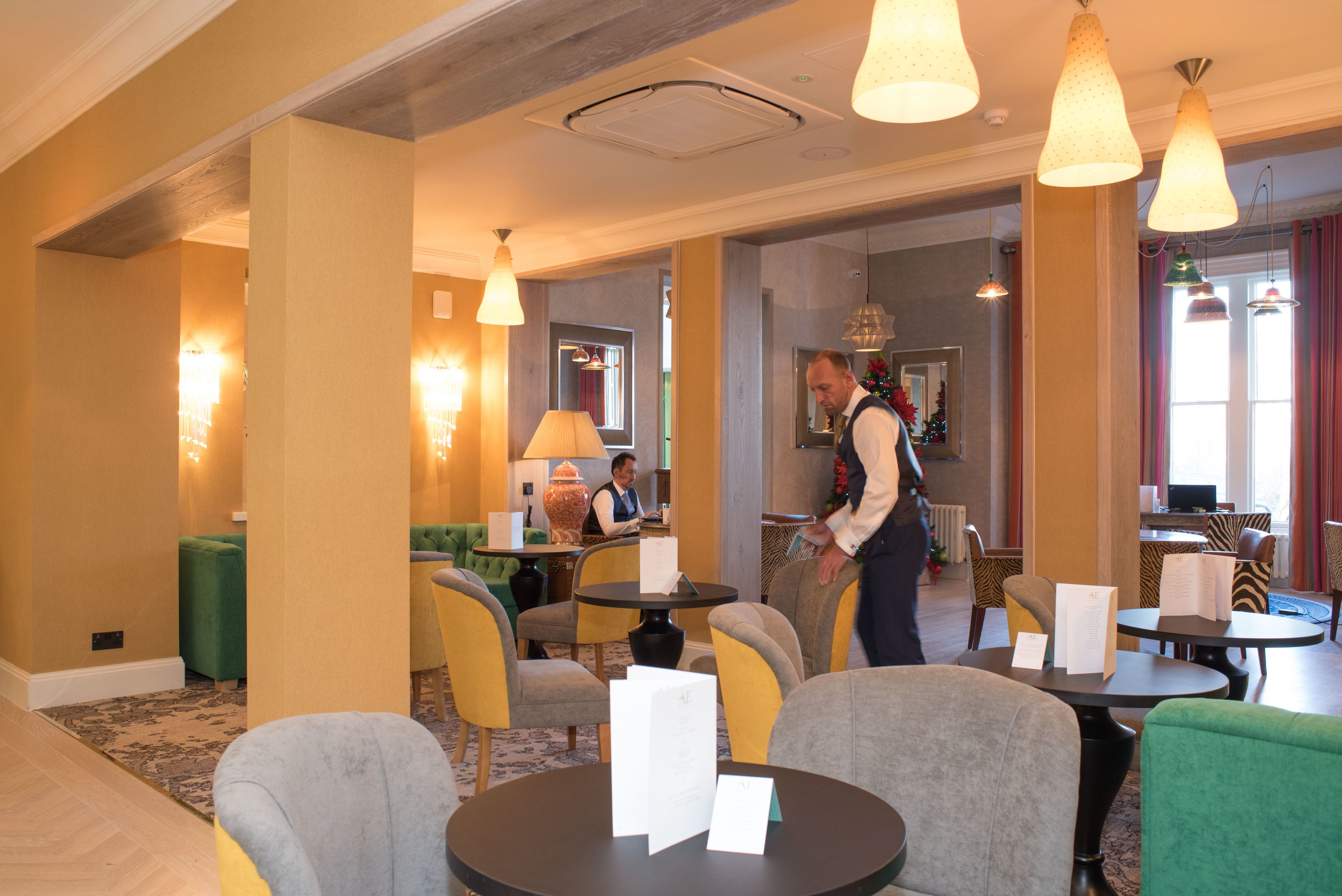 A hotel lobby with round tables, chairs, and a reception area.