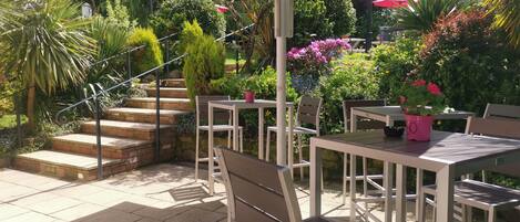 An outdoor patio area with a table and chairs, a staircase, and various plants.