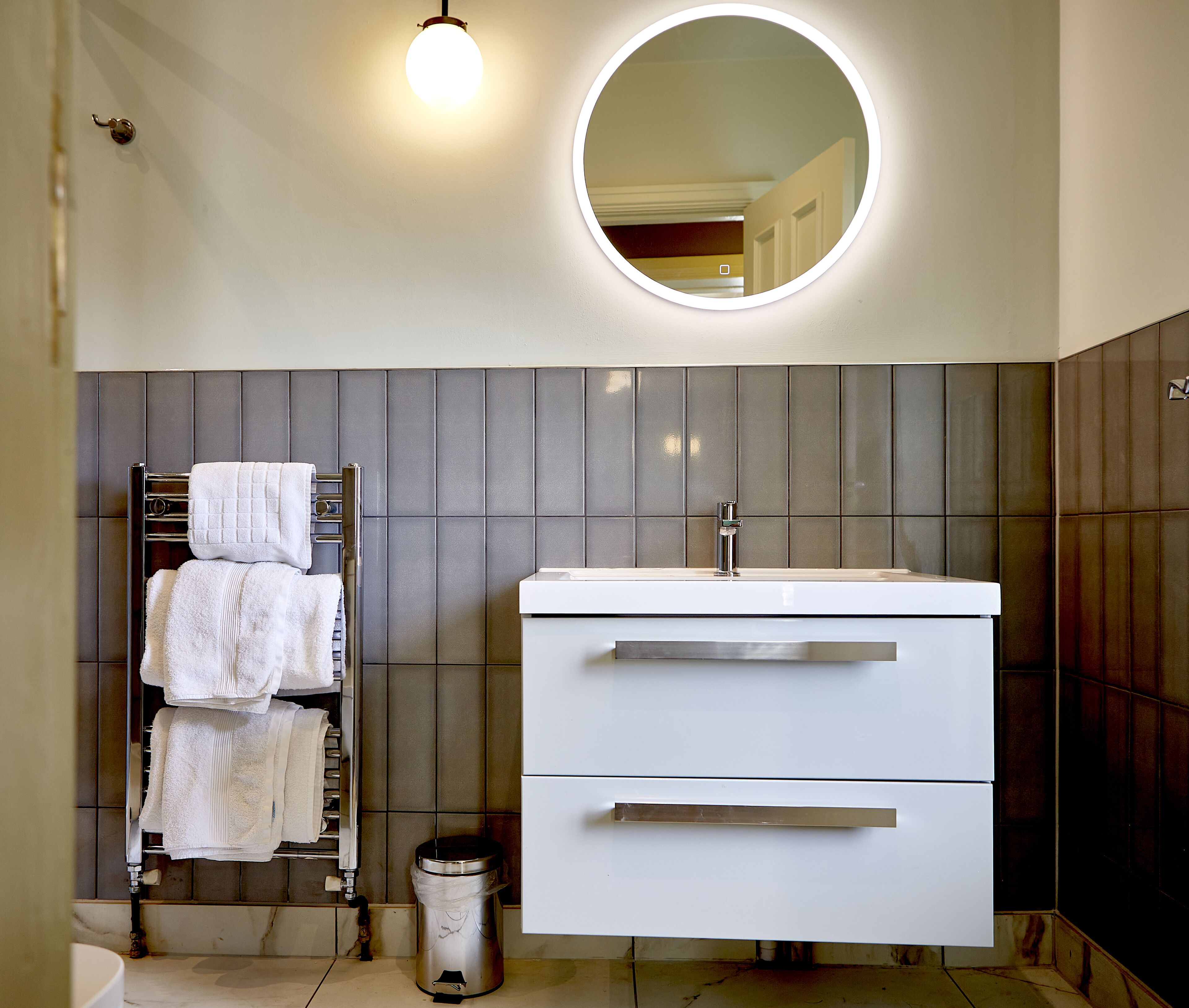 A modern bathroom with a white vanity, a towel rack, and a mirror.