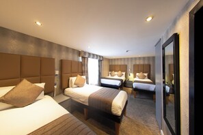 A hotel room with three beds, a large mirror, and a carpeted floor. - Duke of Leinster (London)