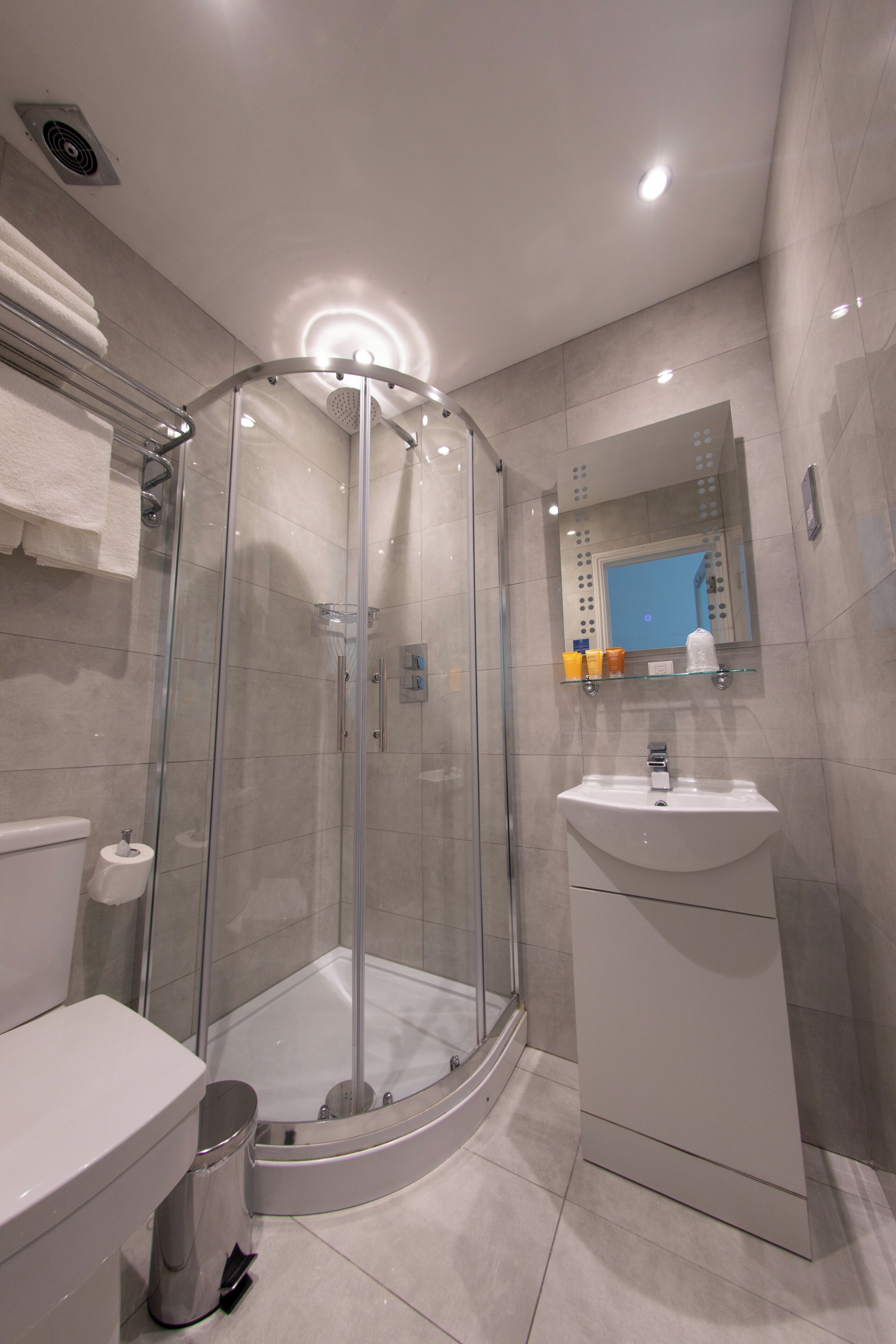 A modern bathroom with a glass-enclosed shower, a white sink, and a mirror above the sink.