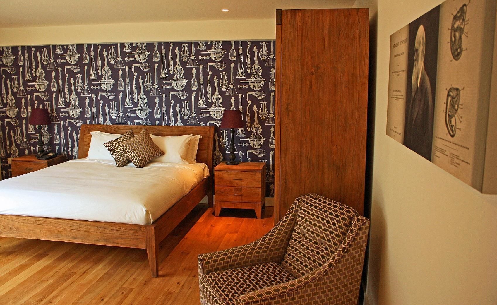 Ein Schlafzimmer mit einem hölzernen Bett, strukturierter Tapete, einem Nachttisch, einem Sessel und einem Wandbild.