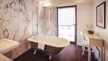 A bathroom with a freestanding bathtub, a toilet, and a vanity with a mirror and bowl.