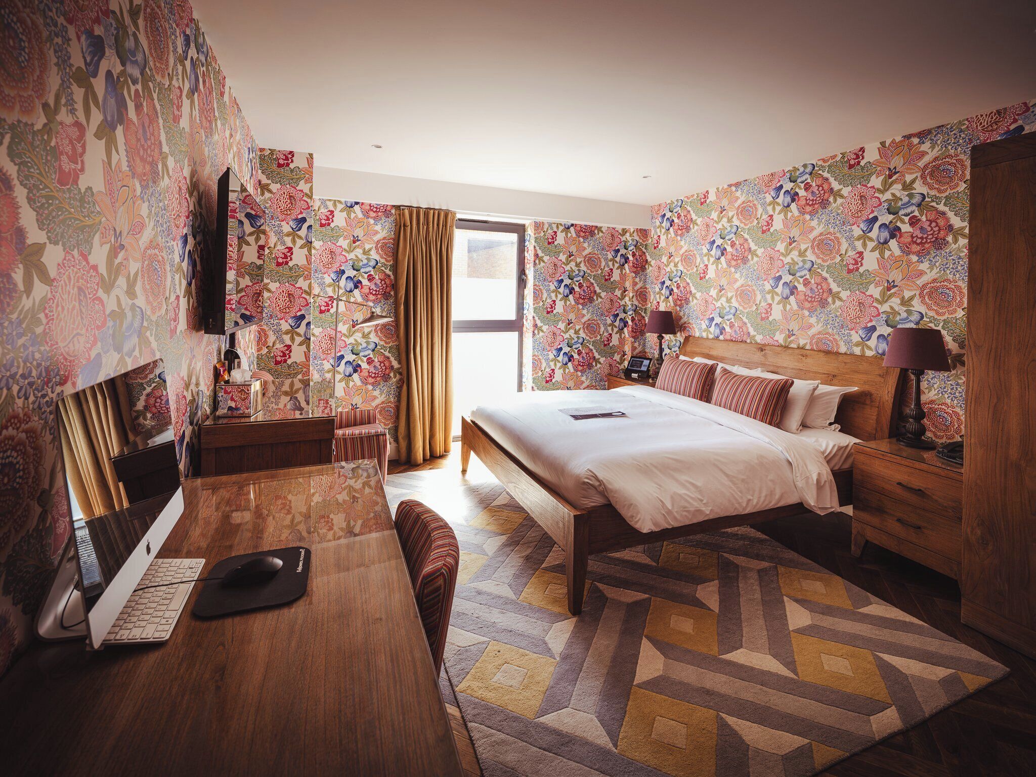 Ein Hotelzimmer mit Bett, Schreibtisch und Fernseher.