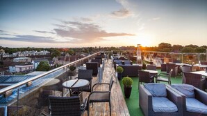 A rooftop terrace with outdoor seating, a view of the city, and a sunset. - The Varsity Hotel & Spa (Cambridge)