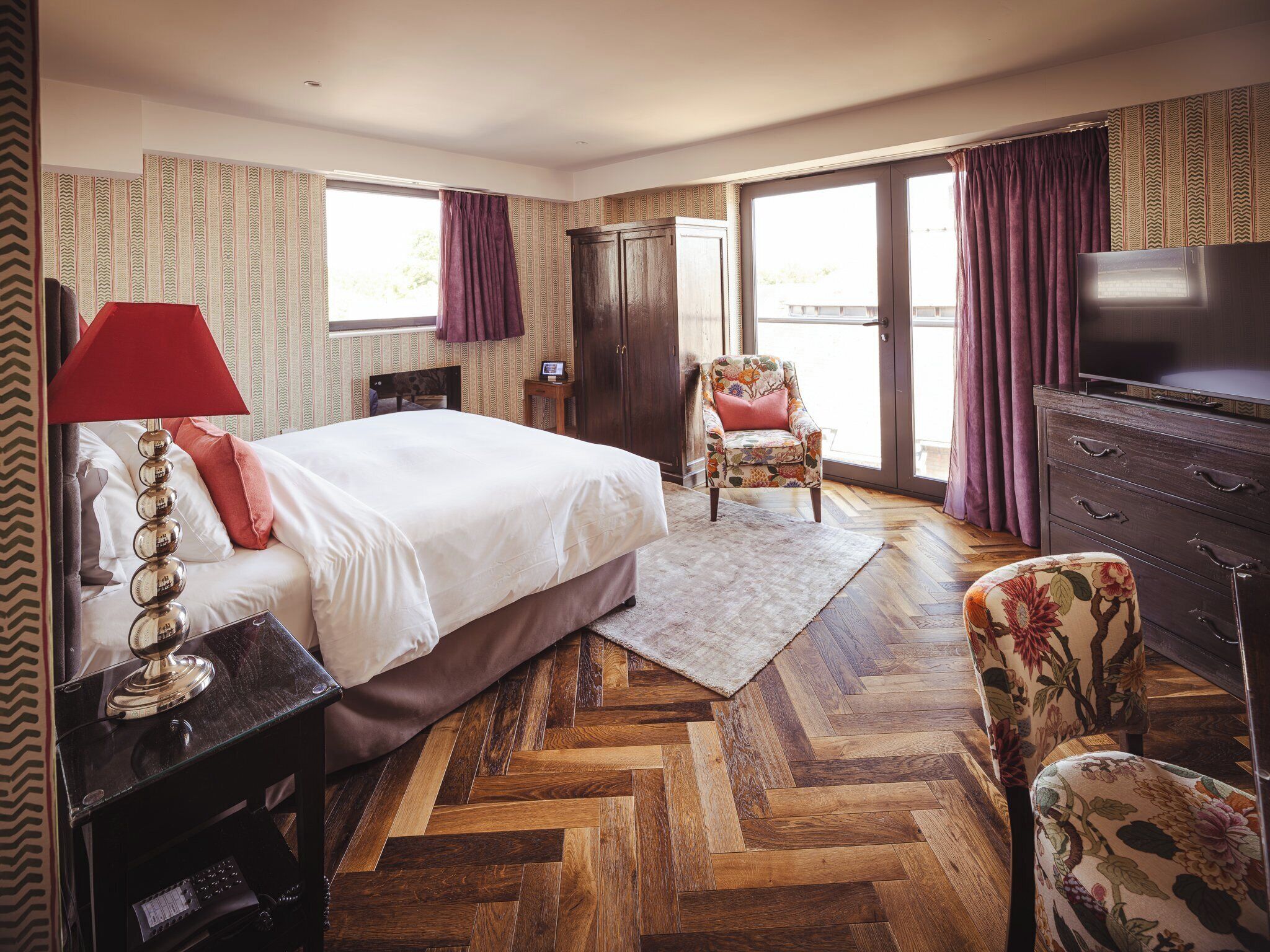 Une chambre à coucher avec un grand lit, une télévision, une chaise et une commode.