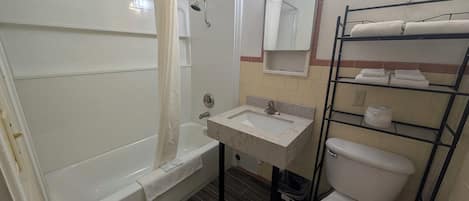 Un baño con bañera, lavabo, inodoro y toallero.