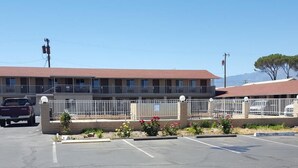 Un motel doté d’un parking, d’un espace clos agrémenté de fleurs et, en arrière-plan, d’une montagne.