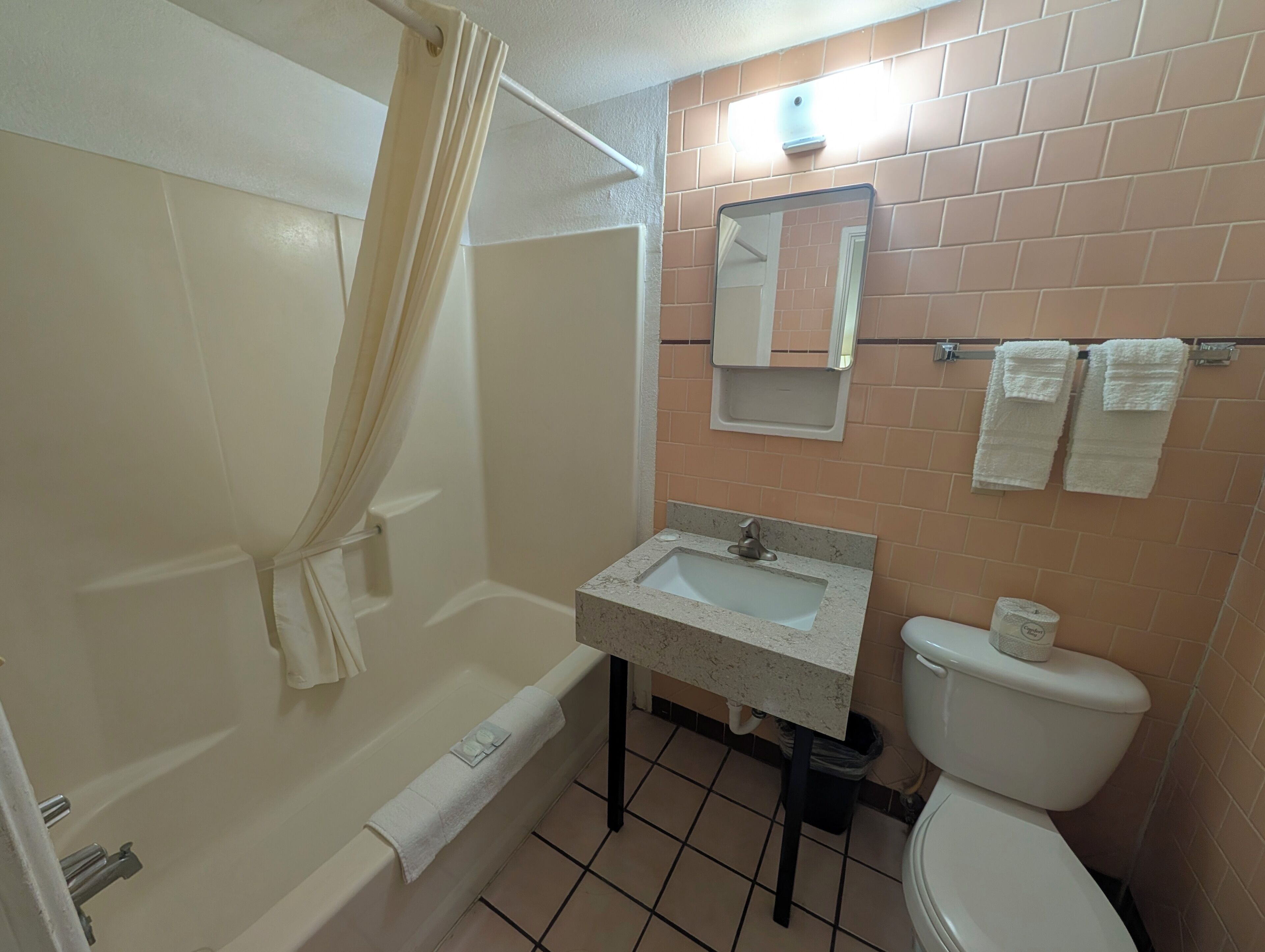 A bathroom with a bathtub, a sink, a toilet, and a mirror.