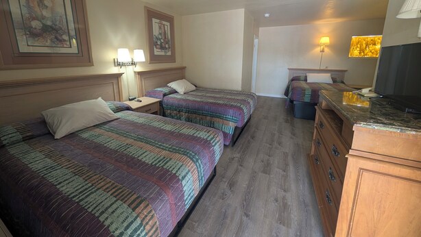 Une chambre d’hôtel avec deux lits, un bureau, une commode et un téléviseur.