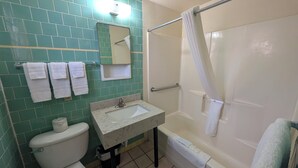 Une salle de bain comprenant des toilettes, un lavabo, un miroir et une baignoire.