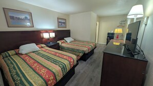 Une chambre d’hôtel avec deux lits, un bureau, un miroir et une télévision.