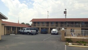Un motel doté d’un parking couvert, de plusieurs chambres et d’un espace extérieur clôturé avec des chaises longues.