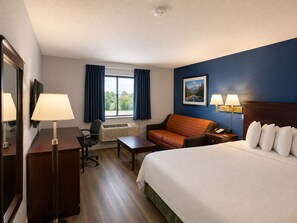 A hotel room with a bed, desk, chair, and a window with curtains. - Corning Inn (Painted Post)