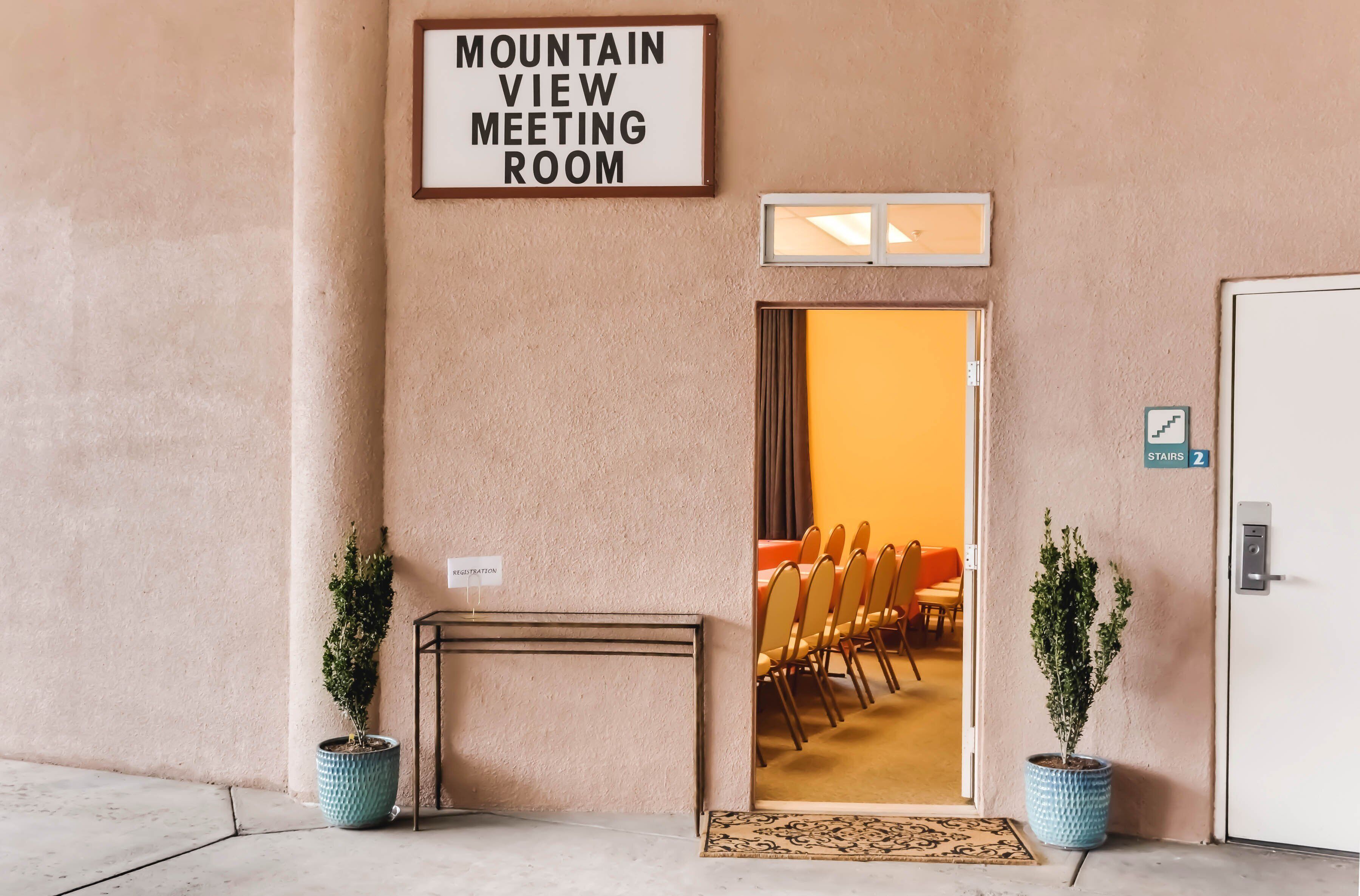 A hotel entrance with a sign reading "Mountain View Meeting Room," a door with a sign indicating "Stairs 2," and two potted plants.