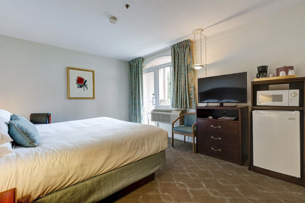 Ein Hotelzimmer mit einem Bett, einem Schreibtisch mit Fernseher, einer Mikrowelle und einem Kühlschrank.