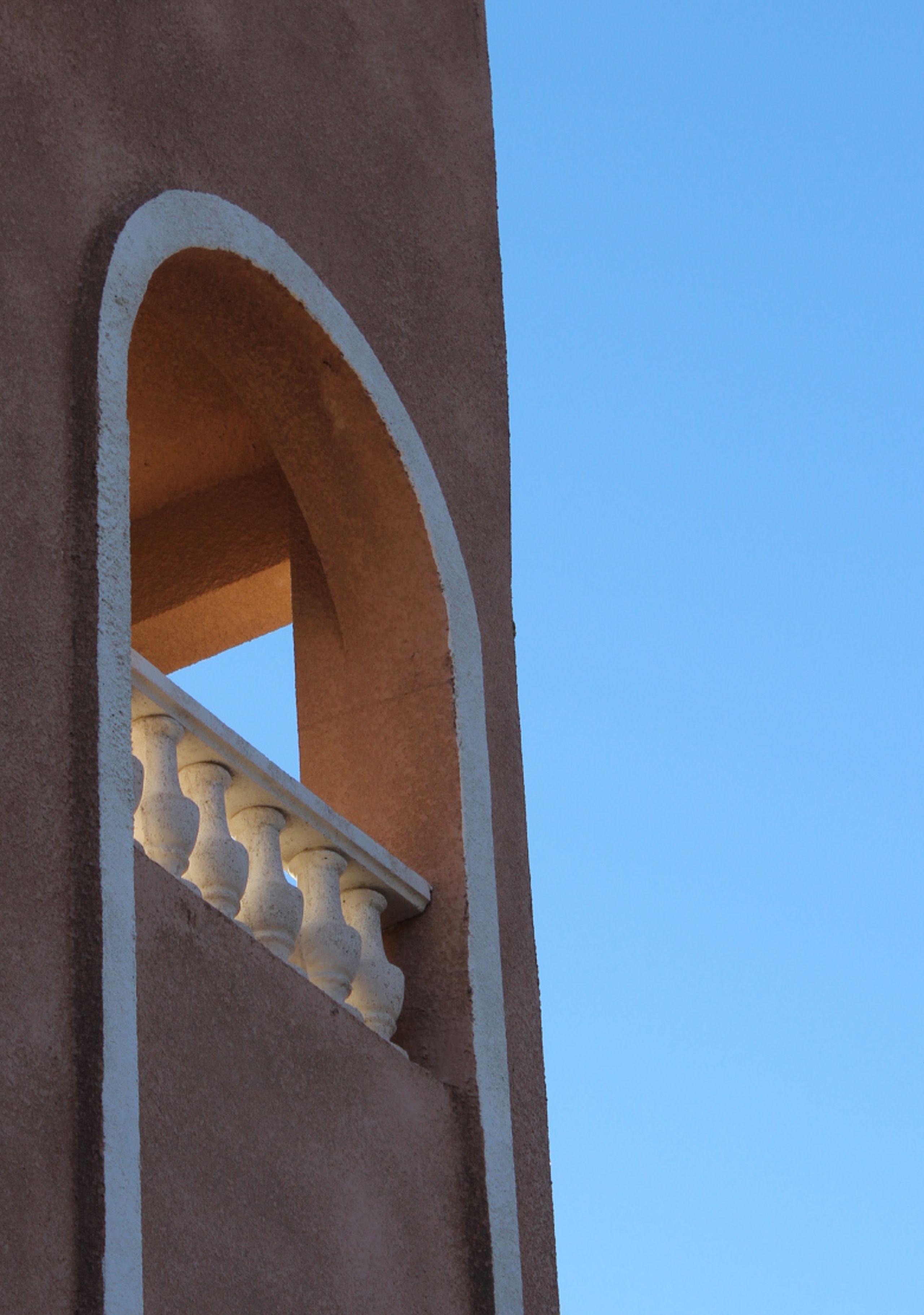 A view of a building's corner with a white balustrade and a clear blue sky.