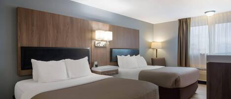 A hotel room with two beds, a wooden headboard, bedside lamps, and a large window with curtains.