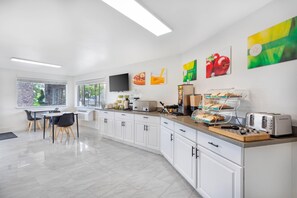 A modern kitchen with white cabinets, a breakfast bar, and various appliances.