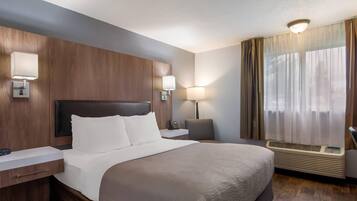 A hotel room with a large bed, bedside tables, a desk, a lamp, a phone, and a window with curtains.