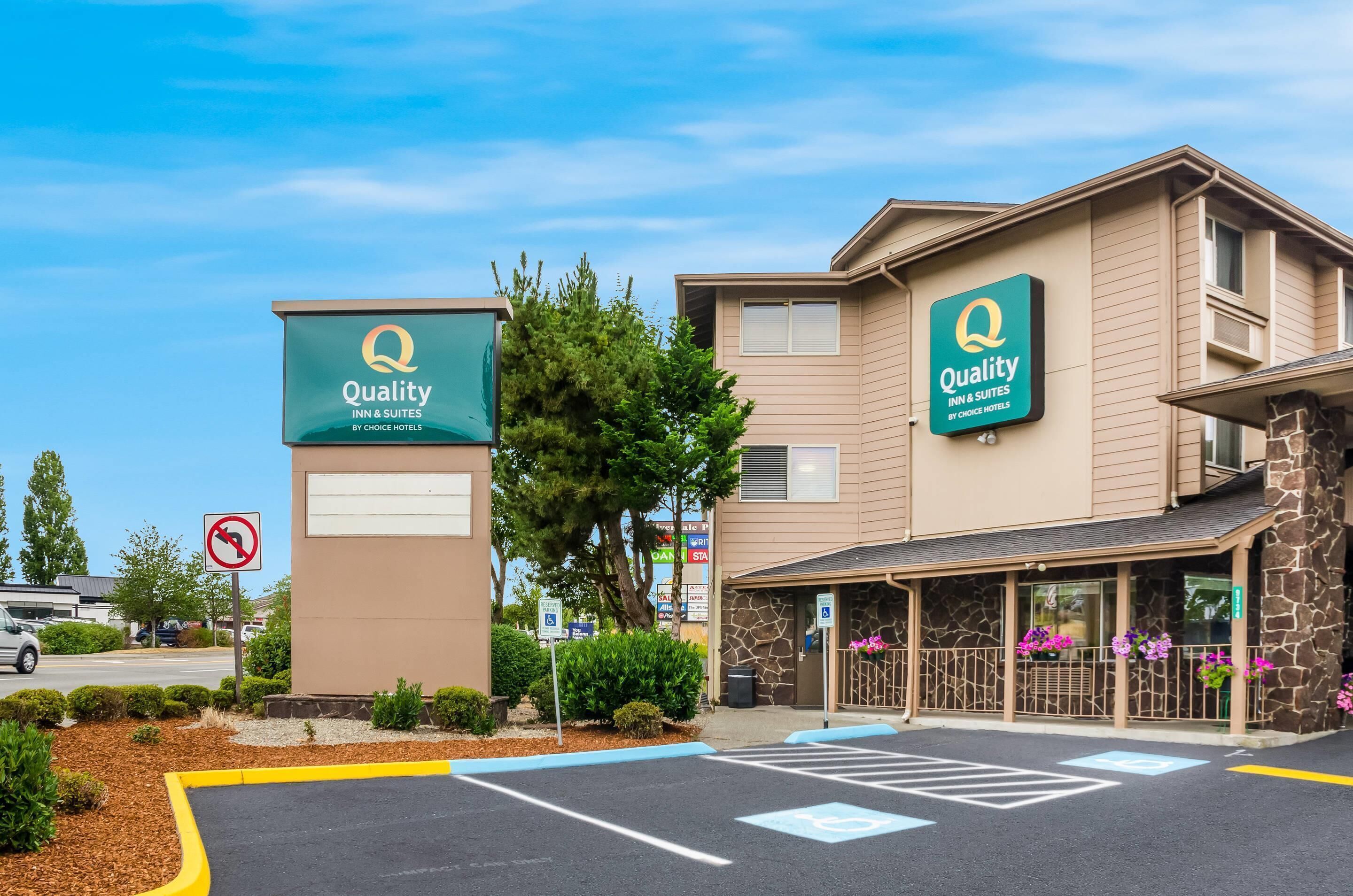 Un hôtel avec une enseigne indiquant « Quality Inn & Suites by Choice Hotels », un parking et un panneau interdisant les demi-tours.