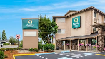 Un hôtel avec une enseigne indiquant « Quality Inn & Suites by Choice Hotels », un parking et un panneau interdisant les demi-tours.