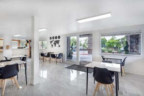 A modern, well-lit dining area with tables and chairs, large windows, and a world map on the wall.