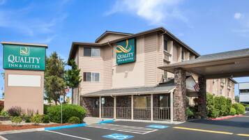 Um hotel com uma placa indicando "Quality Inn & Suites" e uma entrada coberta.