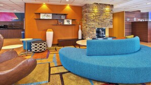 A modern lobby with a blue sofa, a stone accent wall, and a small dining area. - Fairfield Inn & Suites by Marriott Madison West/Middleton (Middleton)