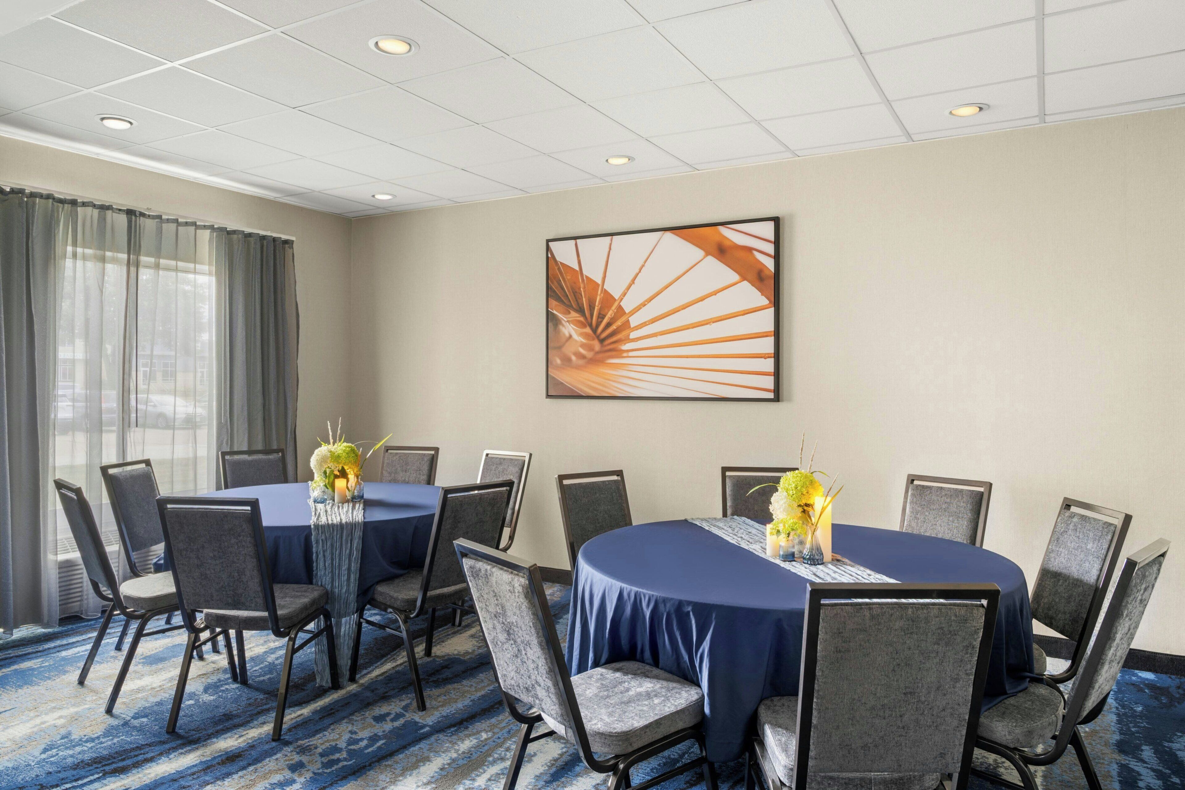 A conference room with a round table, chairs, and a large abstract painting on the wall.