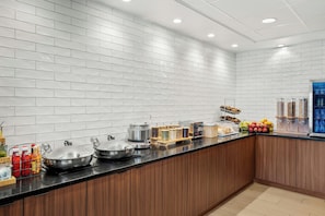 A modern kitchen with white subway tiles, a black countertop, and various food dispensers. - Fairfield Inn & Suites by Marriott Madison West/Middleton (Middleton)