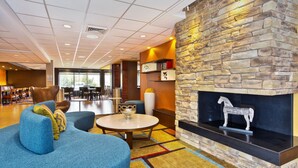 A modern lounge area with a stone fireplace, comfortable seating, and a view of the dining area. - Fairfield Inn & Suites by Marriott Madison West/Middleton (Middleton)