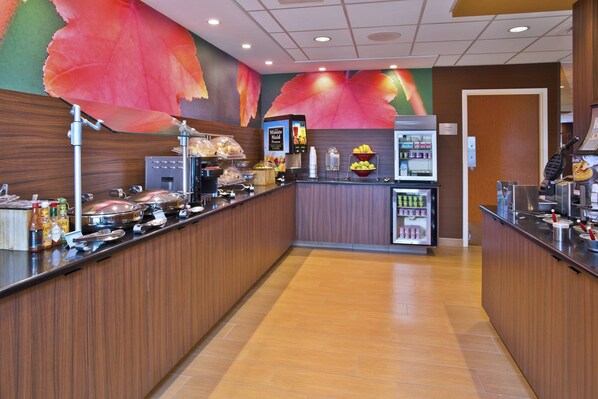 Un espace buffet proposant une variété de plats, un point de distribution de boissons et un réfrigérateur.