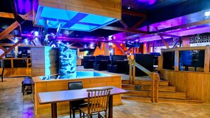 A restaurant with a wooden interior, a central island with seating, and a staircase leading to an upper level. - Douglas Inn & Conference Center (Douglas)