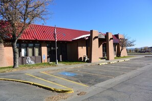 A building with a red roof and brick walls, a parking lot with marked handicapped spaces, and a clear blue sky.